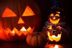A dark room is filled with four jack o lanterns.