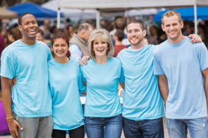 A group of five people in matching blue shirts smile at the camera.