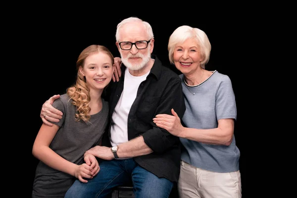 A young teen girl with long blonde hair, and on her left are an older man and woman with light hair.