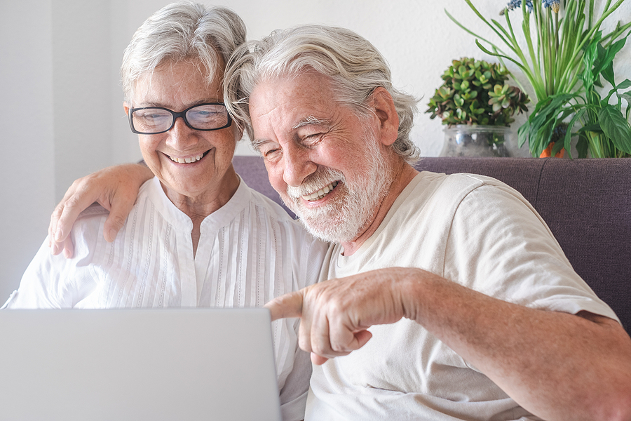 Beautiful Senior Couple Using Laptop Computer Laughing. Serene