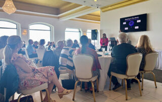 People sitting around tables watching a presentation